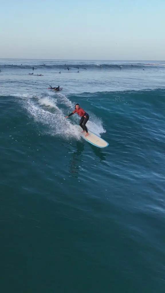 Girl surfing a blue and white mapen longboard in la baie (the bay) imsouane